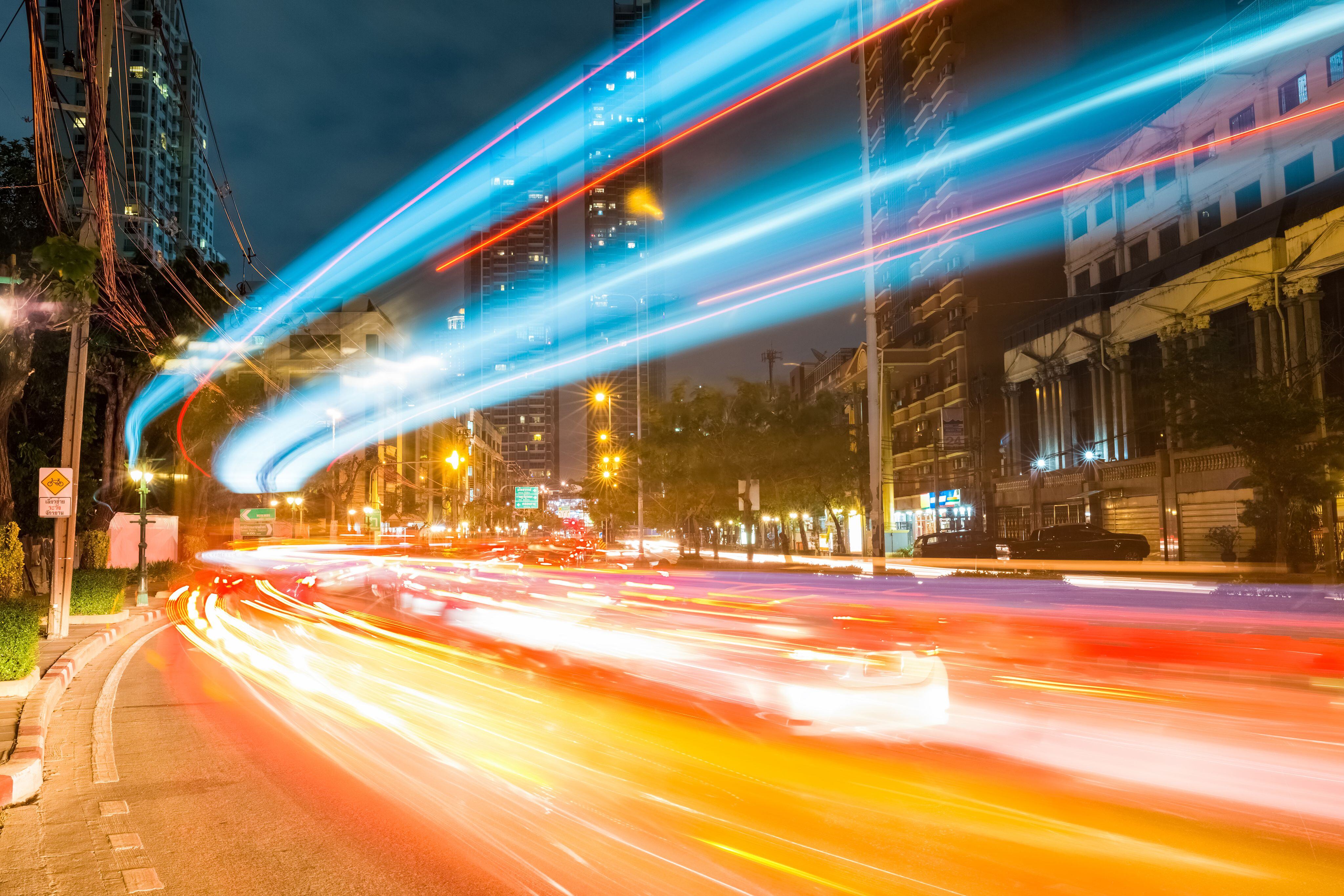 Lichtspuren auf einer nächtlichen Straße symbolisieren die Geschwindigkeit und Dynamik der digitalen Infrastruktur.