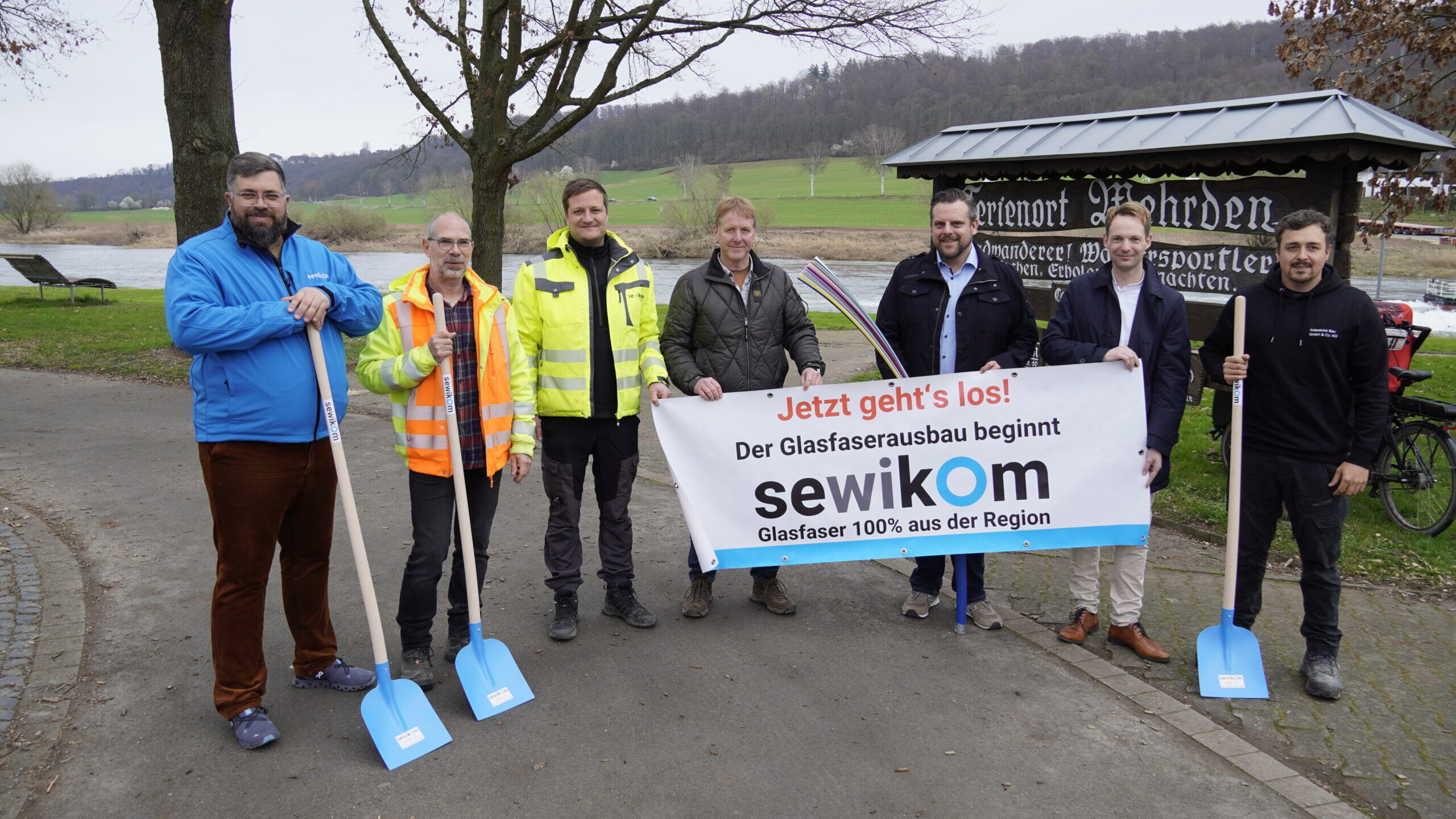 Mehrere Personen halten Spaten und ein Banner zum Start des Glasfaserausbaus in Wehrden