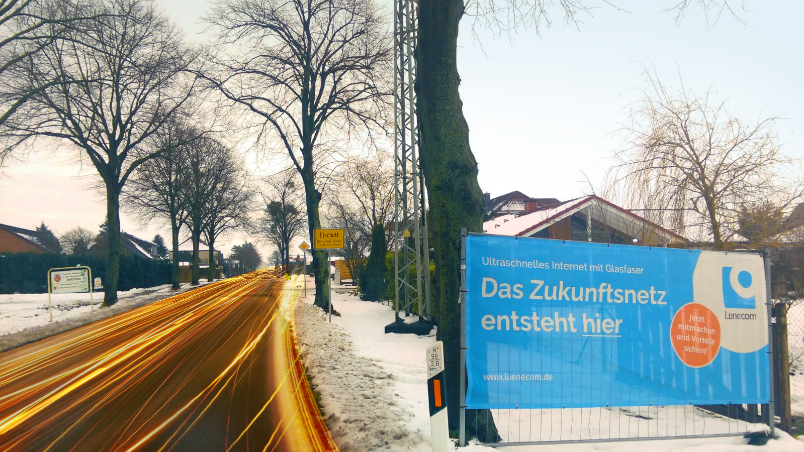 Buntes Lünecom Werbeplakat das im Winter am Strassenrand steht und vom neuen Glasfaser Angebot für Eischott berichtet.